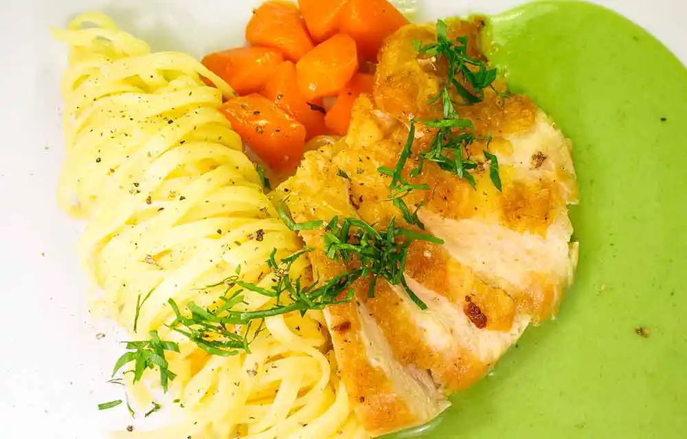 Hühnerbrust auf selbstgemachter Tagliatelle in Bärlauchsoße an glacierten Karotten.