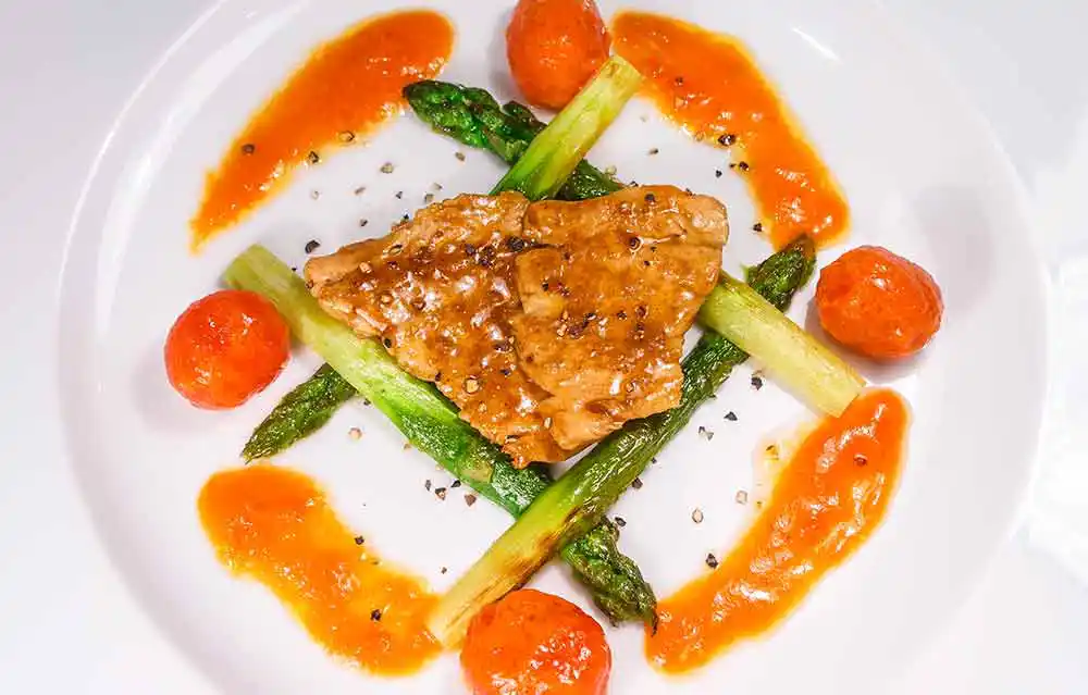 Glacierter Kaninchenrücken mit Kirschtomaten und gebratenem grünen Spargel.