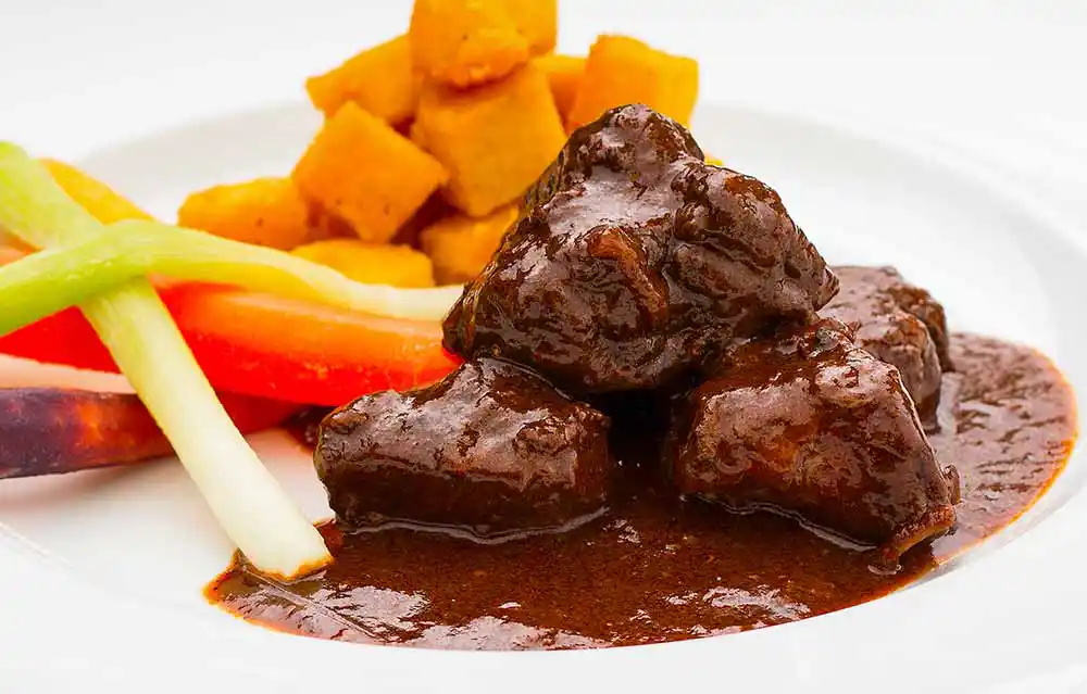 Teller mit Wildschweingulasch und Polenta.