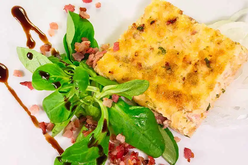 Teller mit Zwiebelkuchen und Feldsalat.