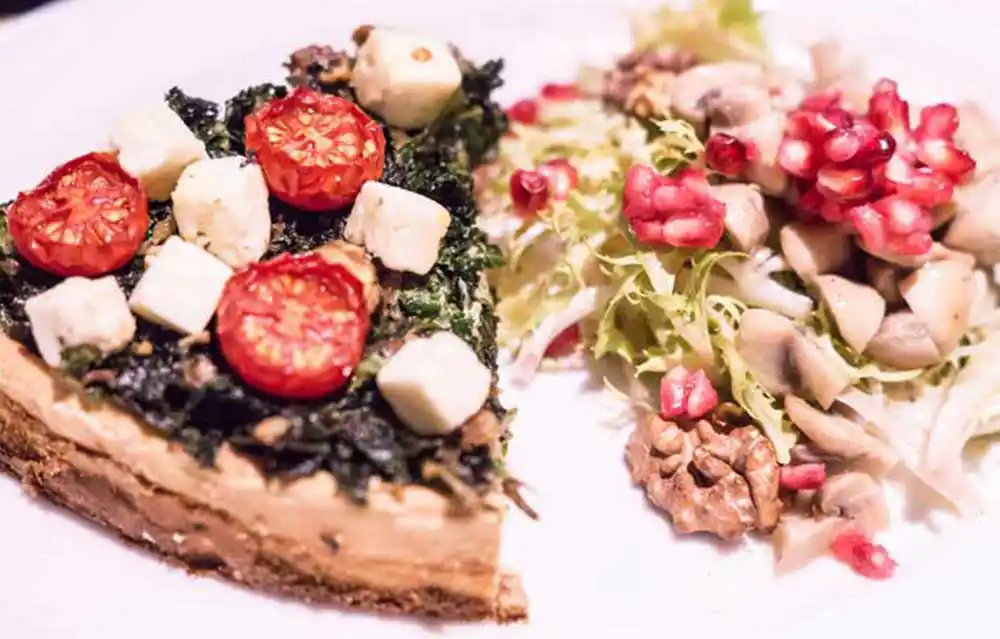 Teller mit Grünkohl-Quiche mit Walnüssen an Frisee-Salat.