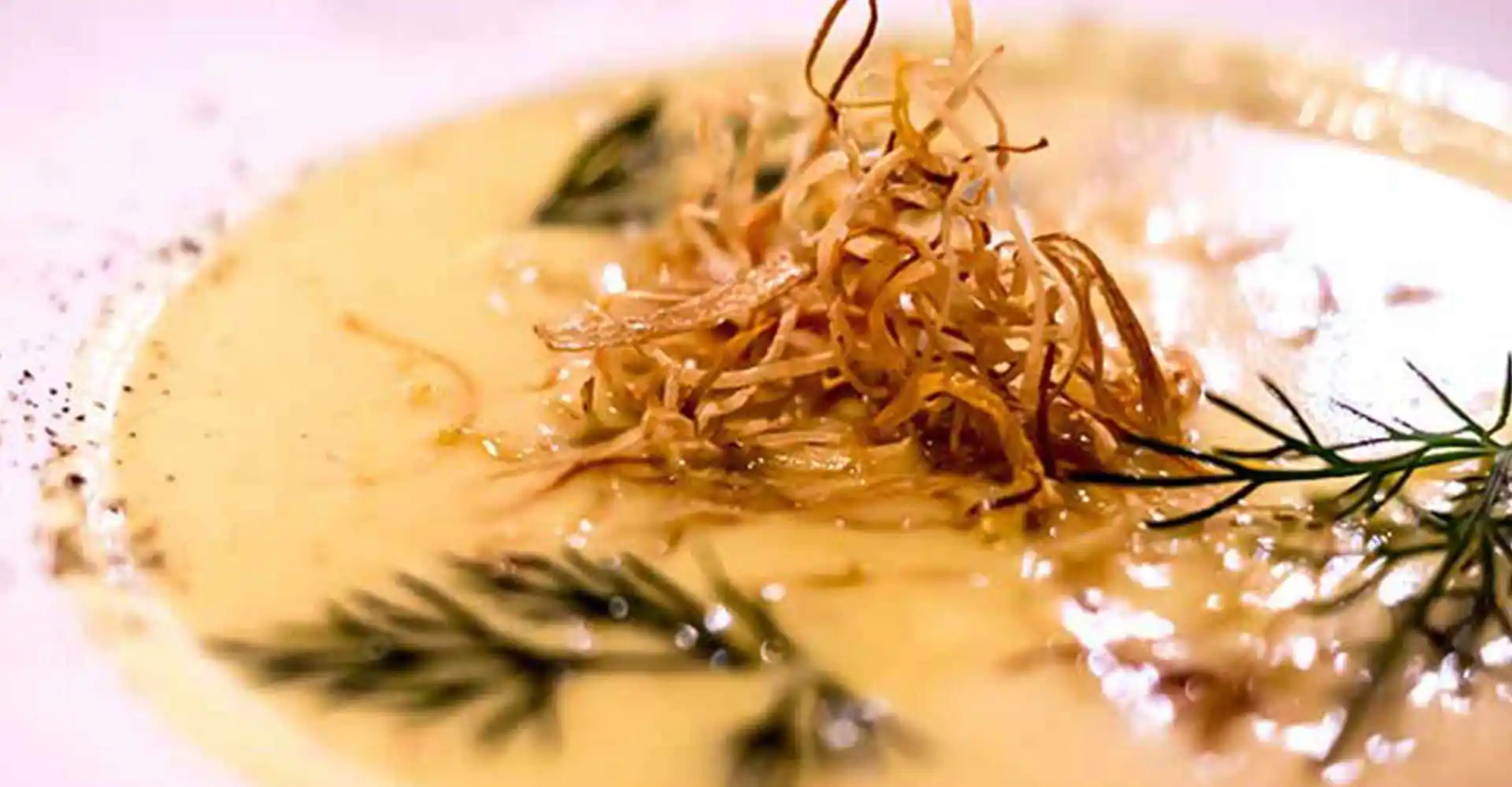 Teller mit Orangen-Fenchelsuppe an Gemüsestroh.