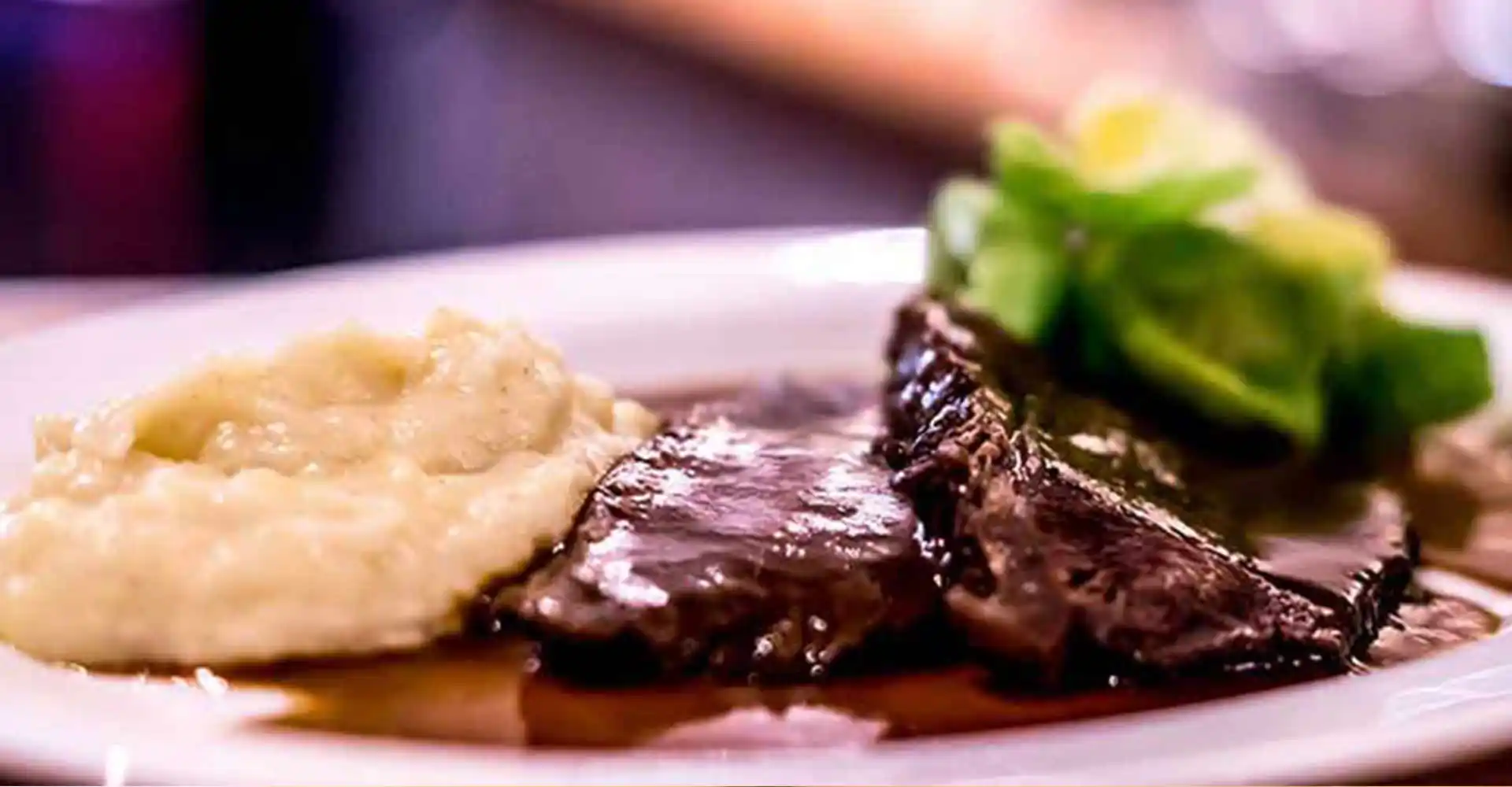 Teller mit Rinderschmorbraten in Rotwein geschmort mit Schwarzwurzelpüree und Rosenkohlblättern.