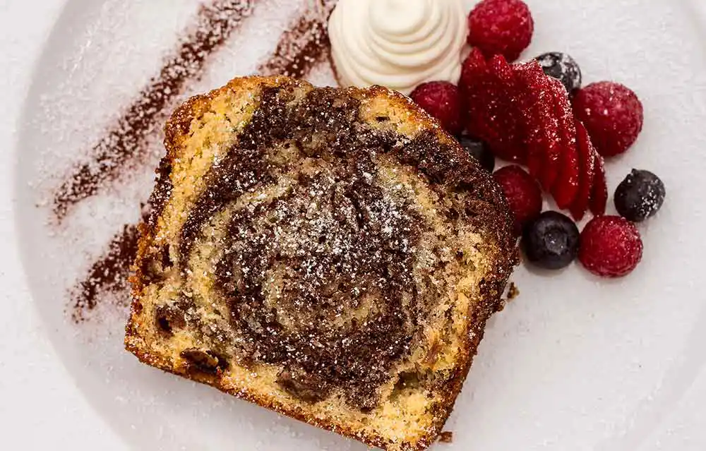 Teller mit Da Baffo's Marmorkuchen garniert mit Schlagsahne und Beeren.